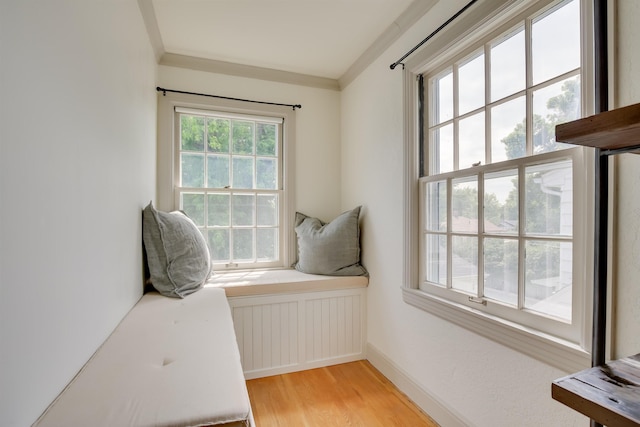 living area with ornamental molding, radiator heating unit, light wood-type flooring, and baseboards