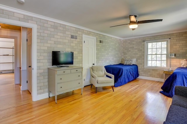 bedroom with a baseboard radiator, ornamental molding, light wood-style floors, a ceiling fan, and brick wall