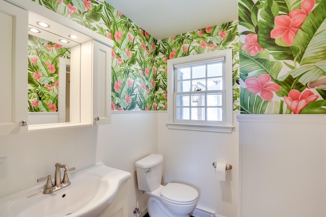 bathroom featuring toilet, wallpapered walls, and a sink