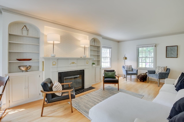 living area with light wood-type flooring, a fireplace with flush hearth, and crown molding