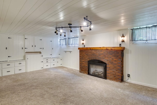 unfurnished living room featuring carpet, a fireplace, wood ceiling, track lighting, and baseboards