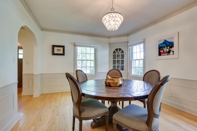 dining space featuring arched walkways, a wainscoted wall, and light wood-style flooring