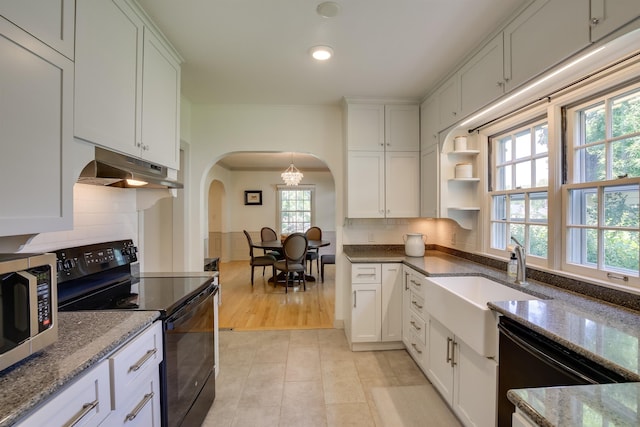 kitchen featuring arched walkways, backsplash, under cabinet range hood, black appliances, and a sink