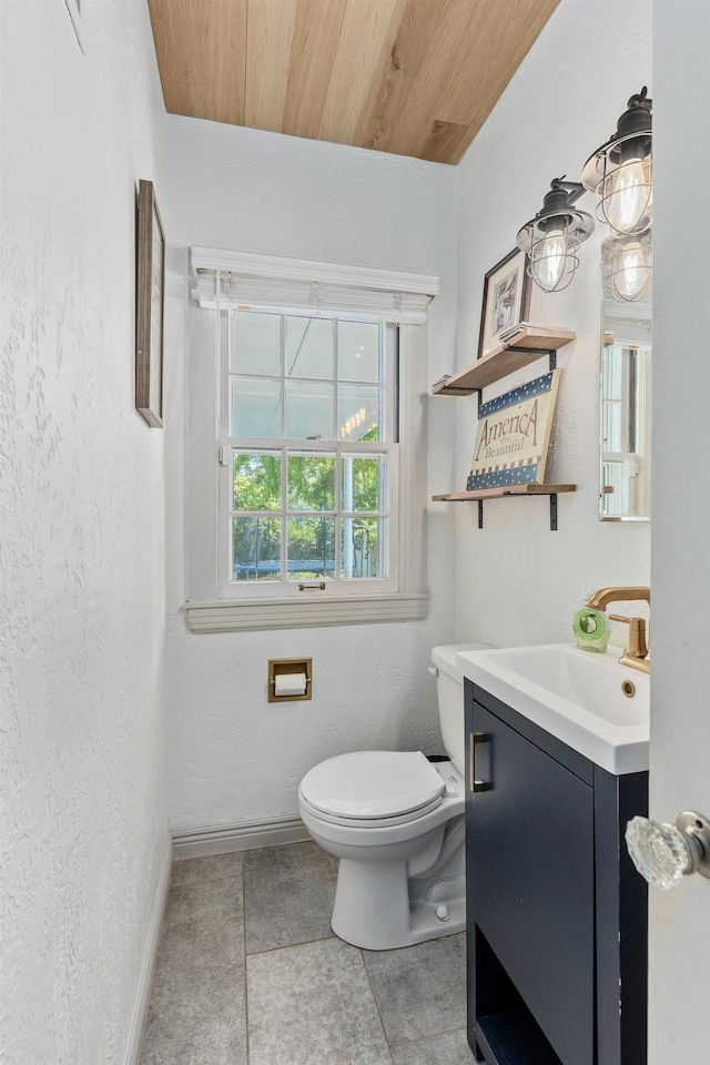 half bathroom featuring a textured wall, tile patterned flooring, toilet, vanity, and baseboards