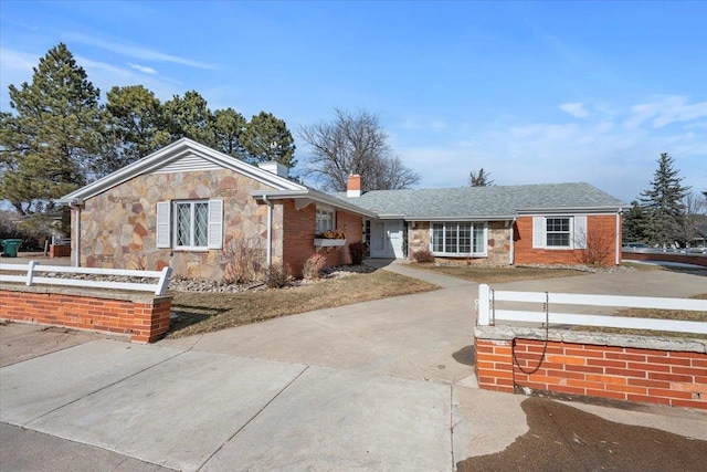 ranch-style home with driveway, stone siding, a chimney, fence, and brick siding