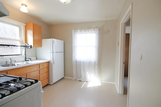 kitchen with baseboards, gas range, freestanding refrigerator, light countertops, and a sink