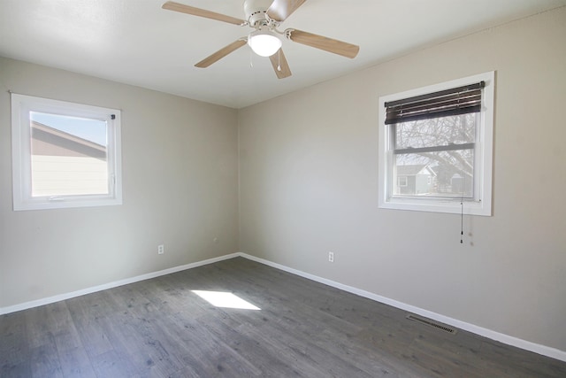 empty room with a ceiling fan, wood finished floors, visible vents, and baseboards