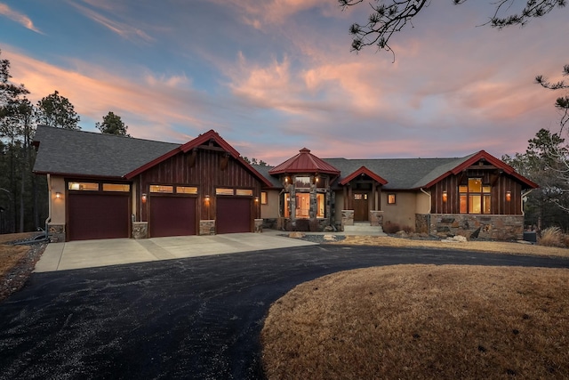 view of front of property featuring a garage, stone siding, and concrete driveway