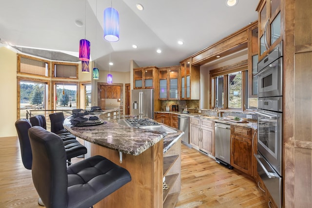 kitchen featuring appliances with stainless steel finishes, a breakfast bar, light wood-style flooring, and brown cabinets