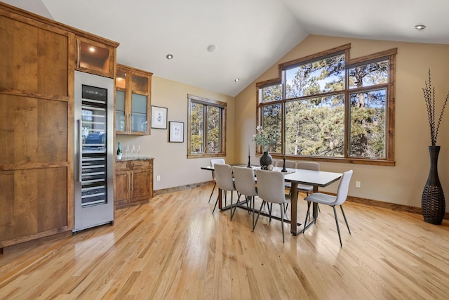 dining room featuring a dry bar, light wood finished floors, wine cooler, and lofted ceiling