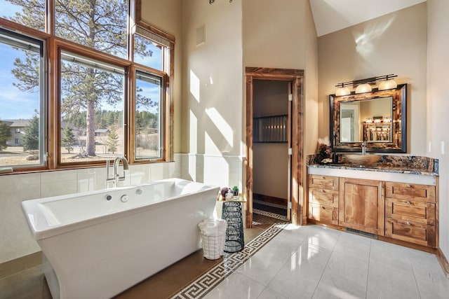 bathroom featuring tile patterned flooring, visible vents, a freestanding bath, and vanity