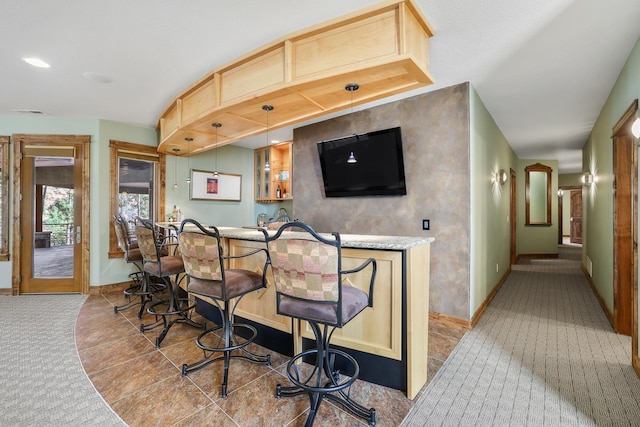 bar with baseboards, bar, tile patterned floors, carpet floors, and pendant lighting