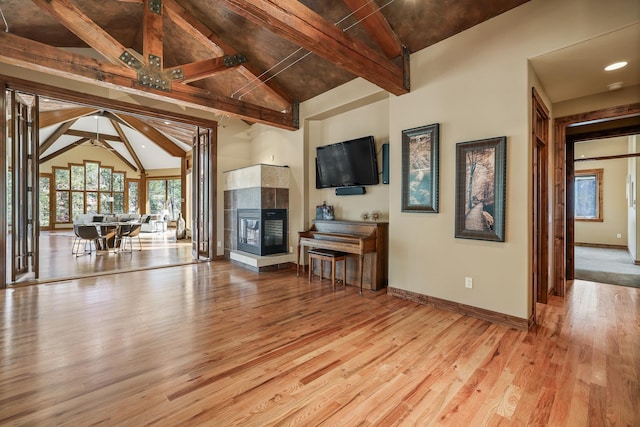 living room featuring baseboards, beam ceiling, a fireplace, wood finished floors, and high vaulted ceiling