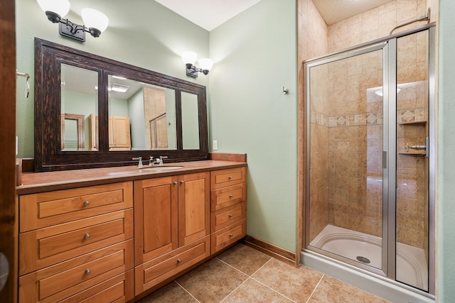 full bath with a stall shower, tile patterned flooring, baseboards, and vanity