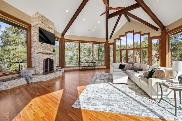 living room with high vaulted ceiling, a fireplace, wood finished floors, and beam ceiling