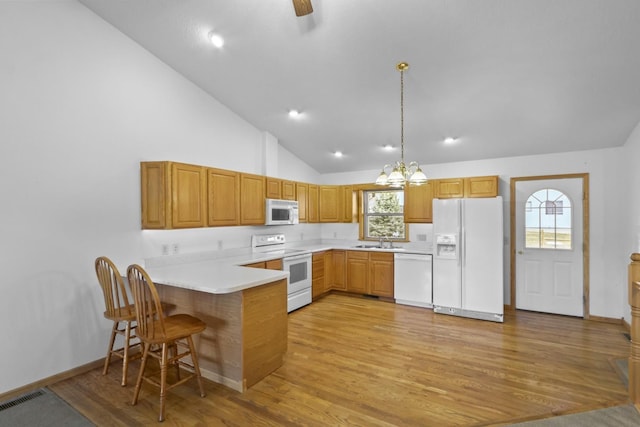 kitchen with white appliances, visible vents, a peninsula, light wood-style floors, and a sink