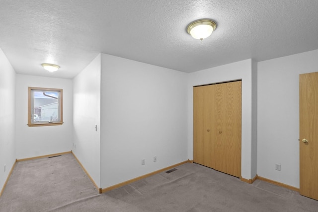 unfurnished bedroom with a closet, carpet, visible vents, and baseboards