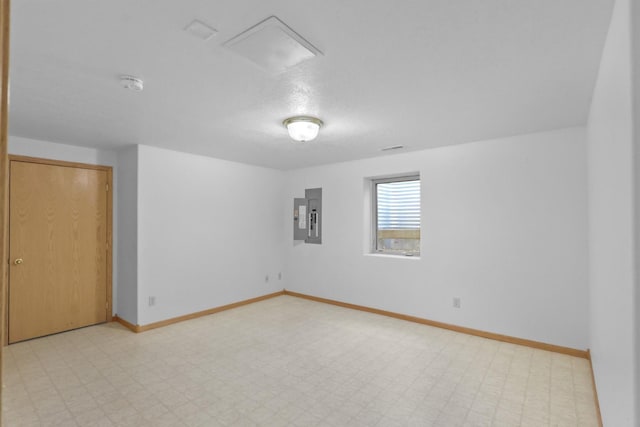 spare room featuring baseboards, electric panel, and light floors