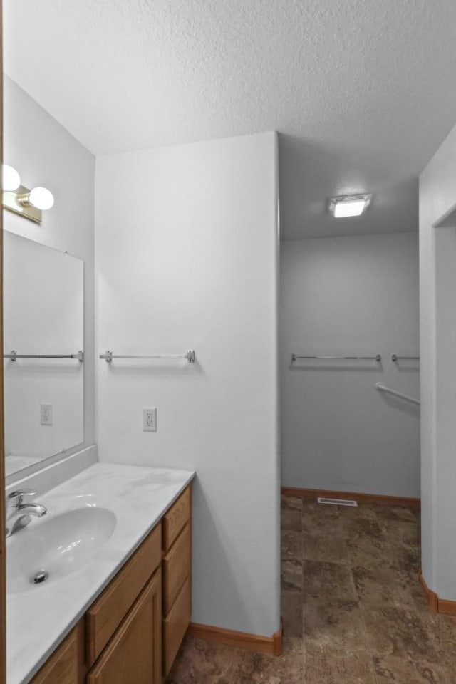 bathroom with baseboards, a textured ceiling, and vanity