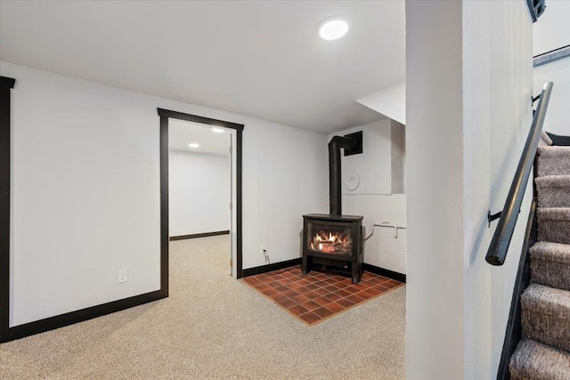 interior space with stairway, carpet flooring, a wood stove, and baseboards