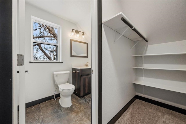 bathroom featuring stone finish floor, baseboards, vanity, and toilet