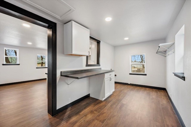 kitchen featuring baseboards, dark countertops, dark wood finished floors, and white cabinets