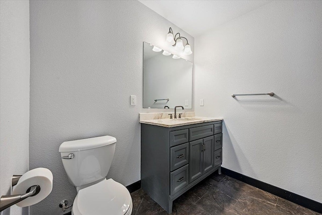 bathroom with a textured wall, toilet, vanity, and baseboards