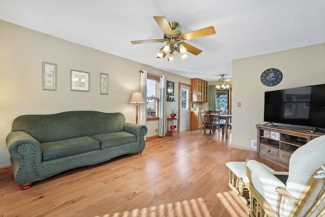 living room featuring baseboards, a ceiling fan, a wealth of natural light, and light wood-style floors