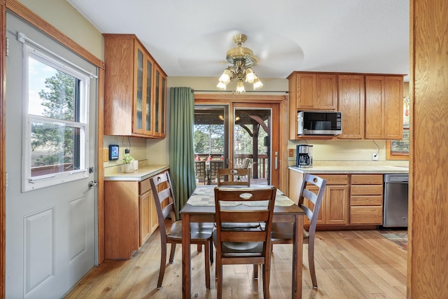 kitchen with light wood-style floors, glass insert cabinets, light countertops, and dishwasher