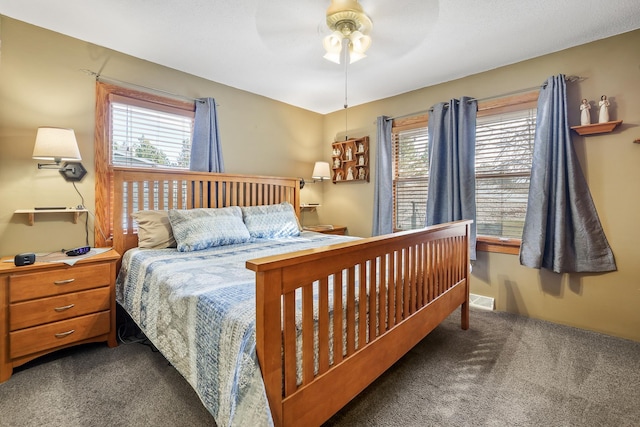 carpeted bedroom with a ceiling fan, visible vents, and multiple windows