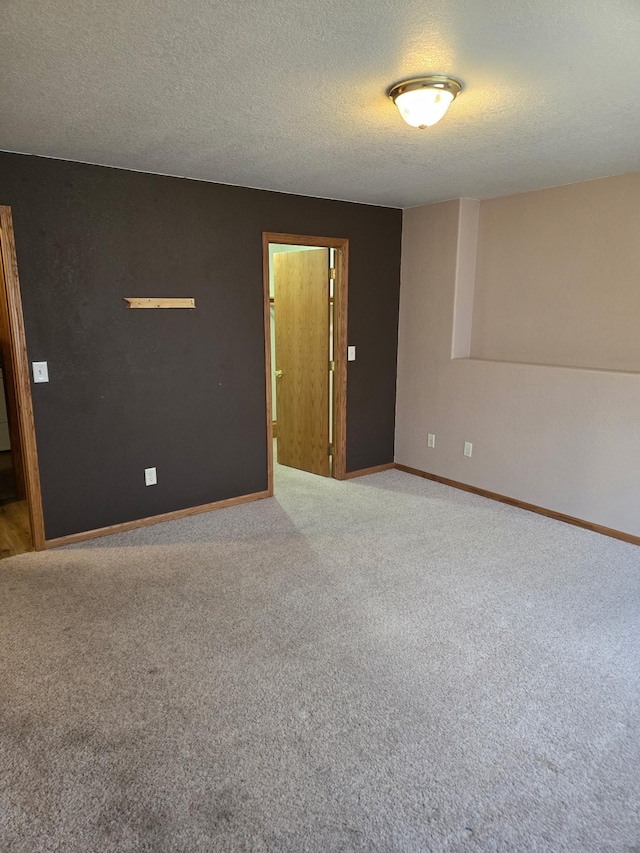 carpeted spare room with a textured ceiling and baseboards