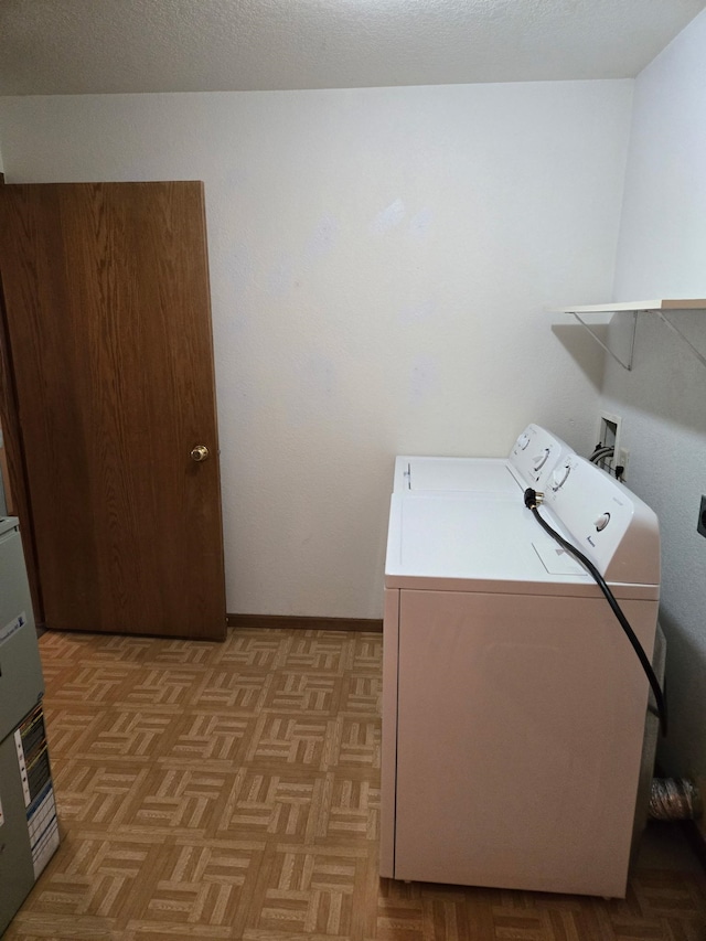 washroom featuring washer / dryer, laundry area, a textured ceiling, and baseboards