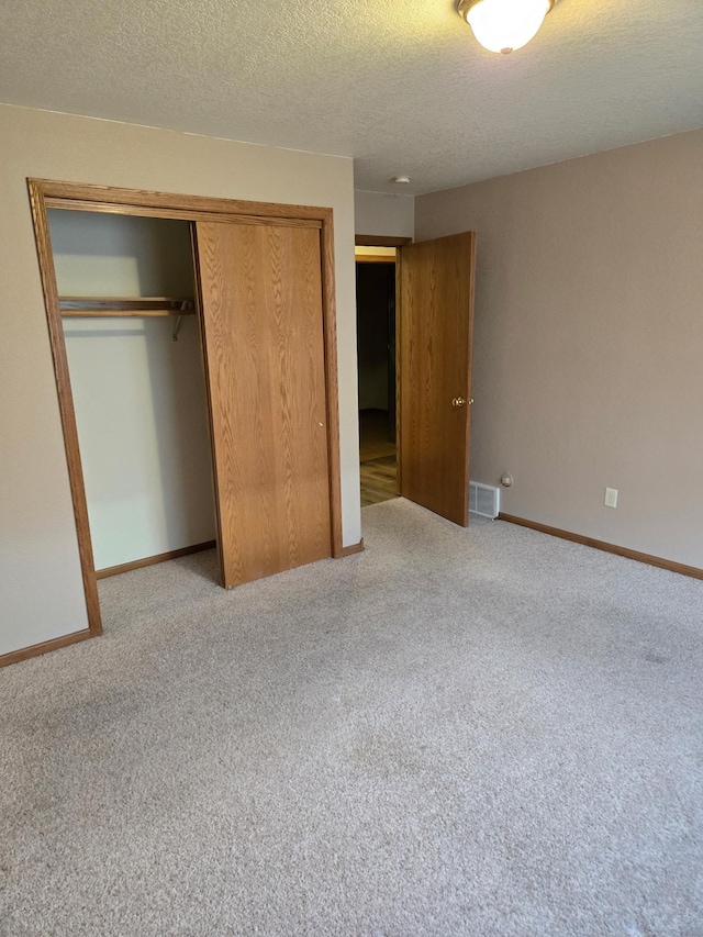 unfurnished bedroom with a closet, carpet flooring, visible vents, and baseboards