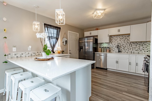 kitchen featuring tasteful backsplash, appliances with stainless steel finishes, white cabinetry, a sink, and a kitchen breakfast bar