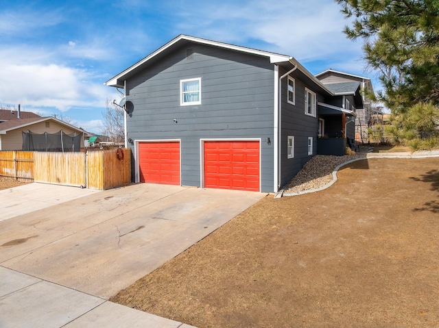 view of home's exterior with a garage, fence, and driveway