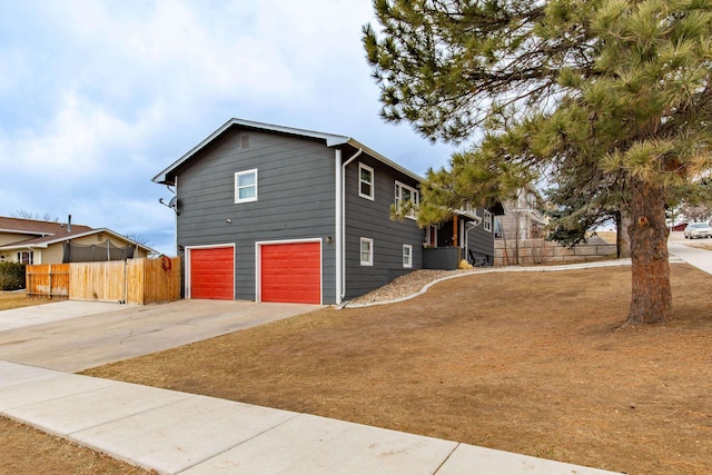 view of front facade featuring driveway, an attached garage, and fence