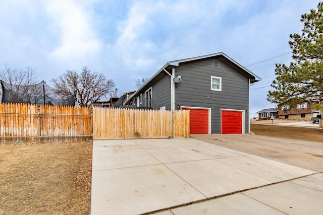 view of home's exterior with concrete driveway, an attached garage, and fence