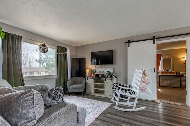 living area with a barn door, a textured ceiling, and dark wood-type flooring