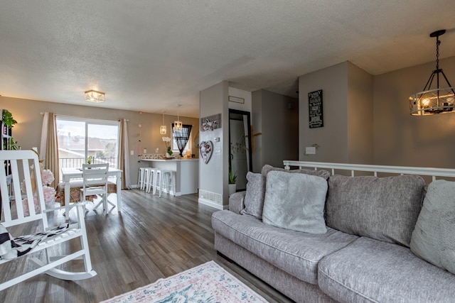 living area featuring an inviting chandelier, a textured ceiling, baseboards, and wood finished floors