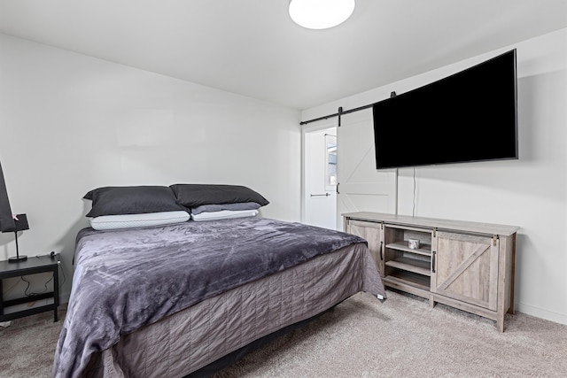 bedroom featuring light carpet, a barn door, and baseboards