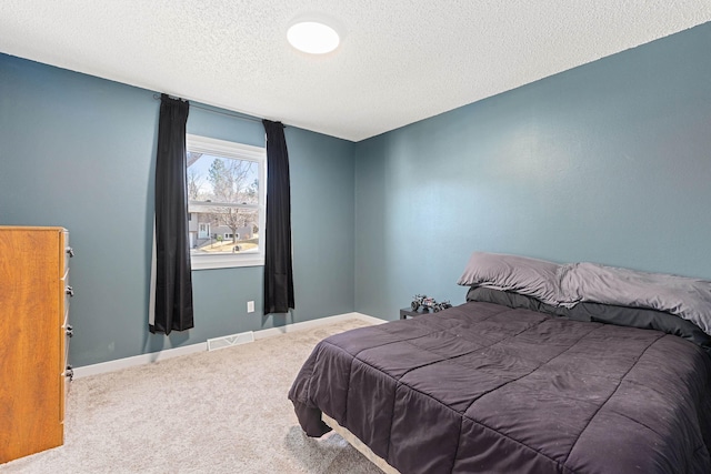 carpeted bedroom with visible vents, a textured ceiling, and baseboards