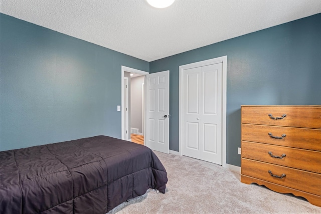 bedroom with a closet, carpet flooring, a textured ceiling, and baseboards