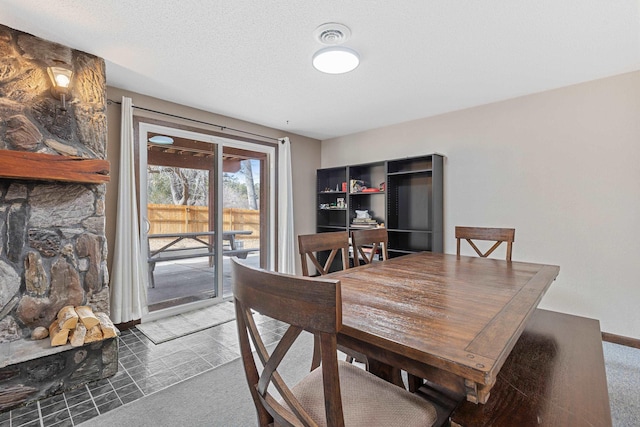 carpeted dining space with a textured ceiling and baseboards