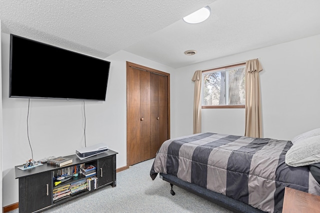 carpeted bedroom with a textured ceiling, a closet, visible vents, and baseboards