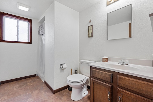 bathroom featuring toilet, baseboards, and vanity