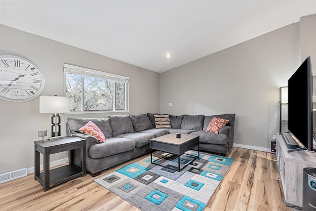 living room featuring visible vents, light wood-style flooring, and baseboards