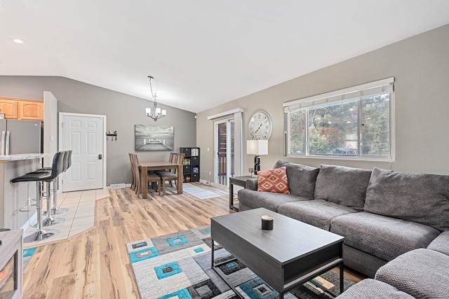 living area with lofted ceiling, light wood-style floors, baseboards, and a chandelier