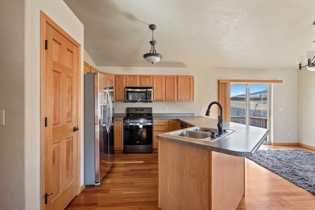 kitchen with stainless steel appliances, light wood-style floors, a peninsula, and a sink