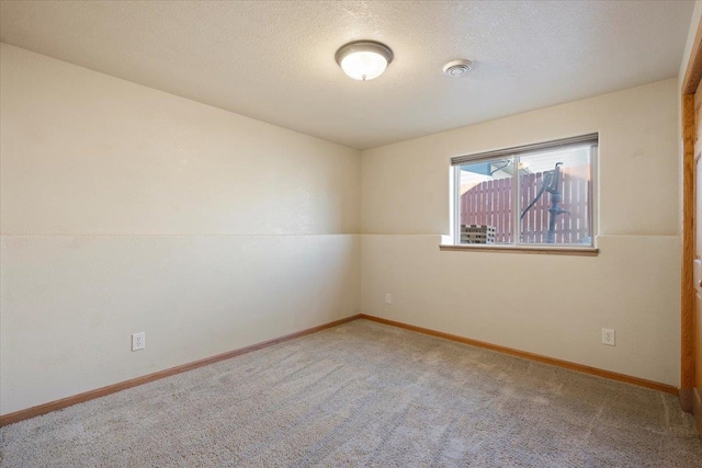 carpeted empty room with baseboards and a textured ceiling