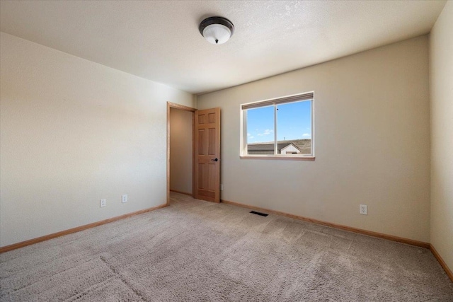 carpeted empty room with a textured ceiling, visible vents, and baseboards